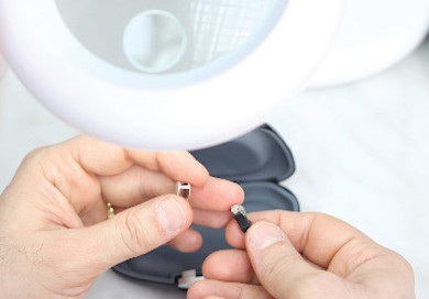 An audiologist repairs hearing aids